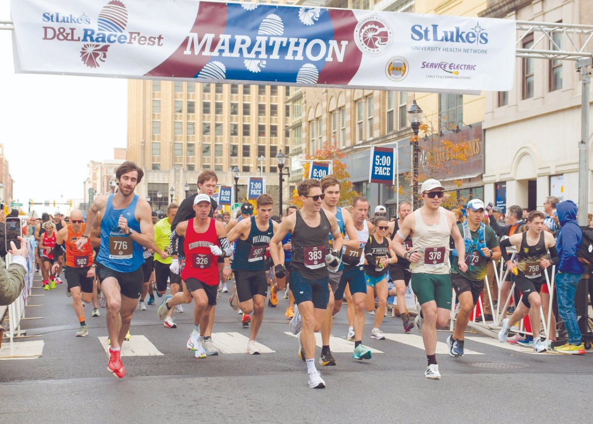 Runners start the St. Luke's D&L RaceFest marathon under a banner on a city street.